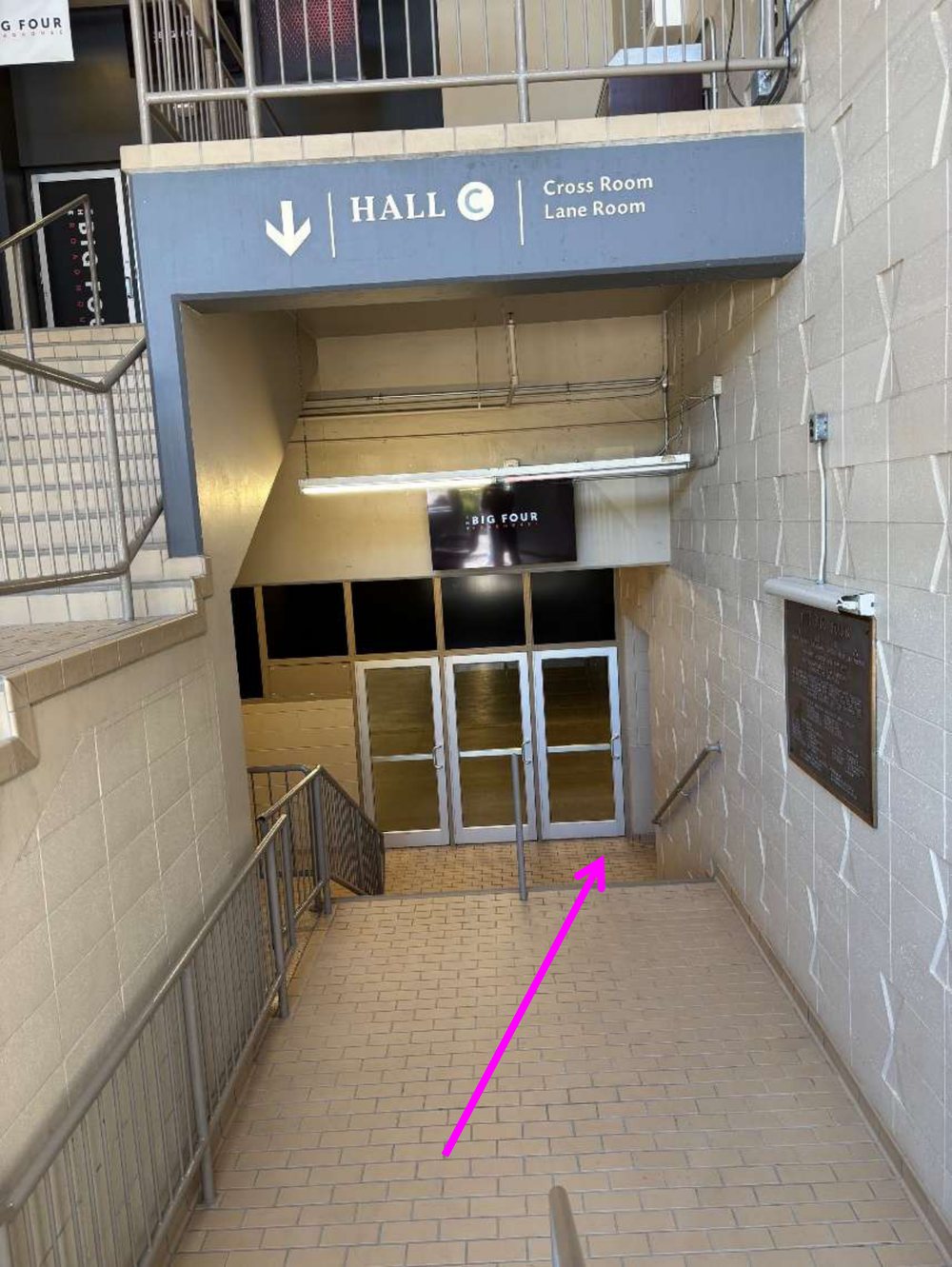 A stairway going down toward the Hall C doors, with a Hall C sign and a down arrow above it.