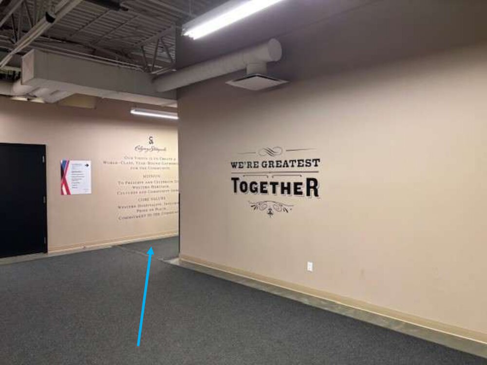 A Level 2M hallway with a We Are Greatest Together wall and an arrow pointing left around the corner.