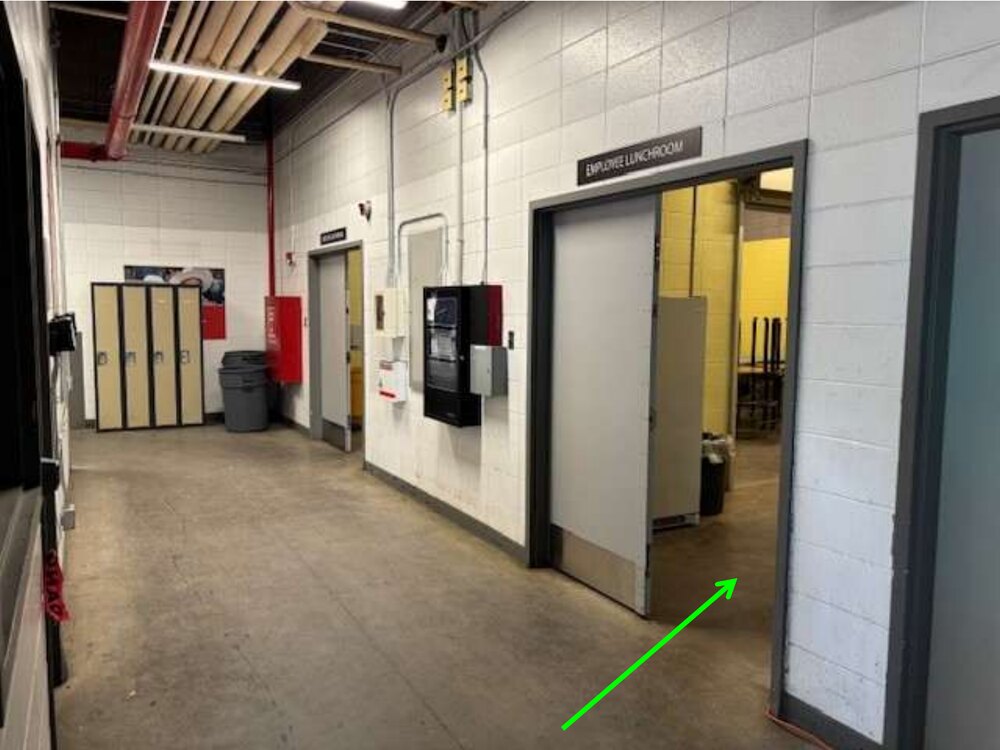 The GMC employee lunchroom doorway, with a green arrow pointing inside and day-use lockers along the hallway.